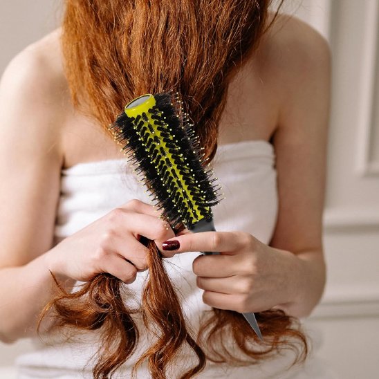 femme se coiffe avec brosse a cheveux jaune cylindrique